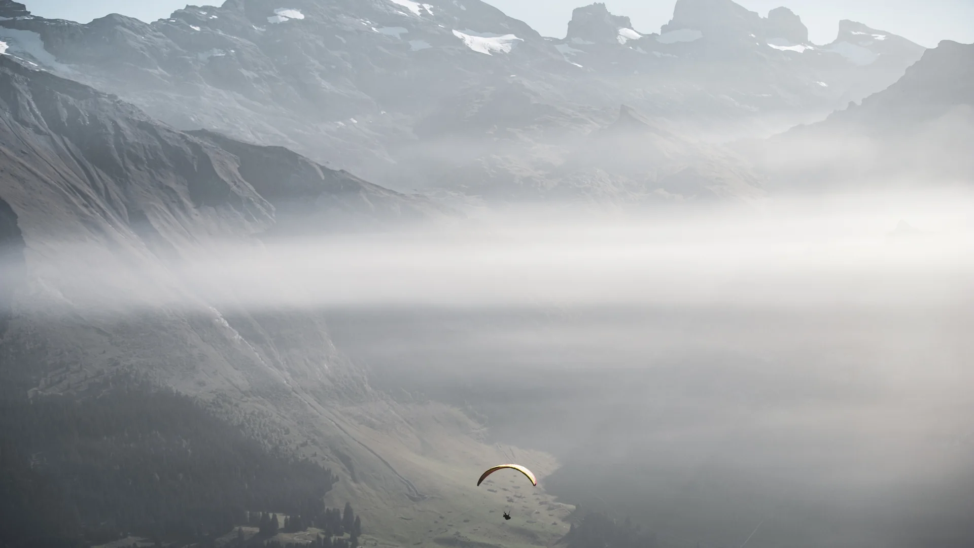 Gleitschirmpilot über einem nebligen Alpental als Sinnbild für Überblick und präzise Umsetzung