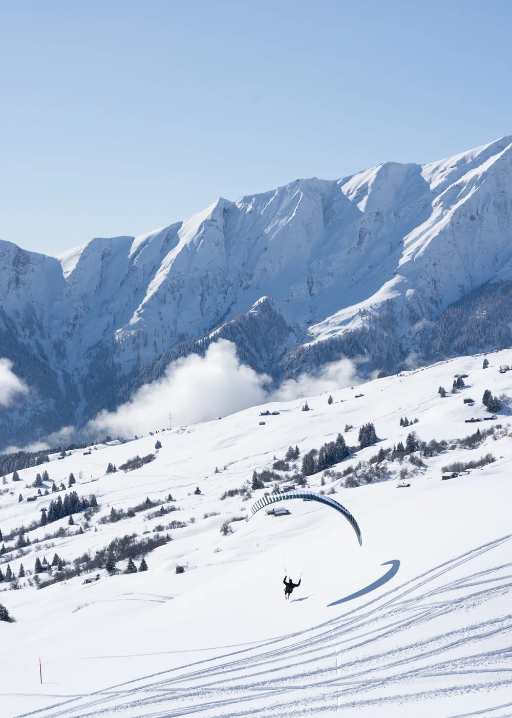 Speedflying über einem verschneiten Berghang
